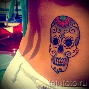 Фото тату: красочный сахарный череп (sugar skull) на женском боку. Яркие цвета, детальная проработка, мексиканский стиль.