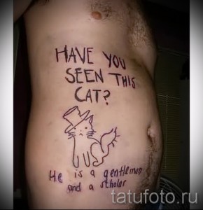 Фото татуировки с надписью "Have you seen this cat? He is a gentleman and a scholar" и изображением кота в цилиндре на боку. Рисунок выполнен в красно-коричневых тонах.