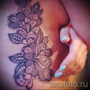 Фото татуировки с кружевным узором на боку. Рисунок выполнен в черных тонах, создавая изящный и женственный образ.
