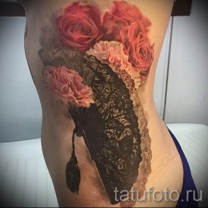 Фото тату: красивый рисунок с изображением кружева и роз, выполненный на боку девушки. Татуировка выполнена в реалистичном стиле с использованием красных и черных оттенков.
