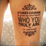 Фото татуировки с мотивирующей надписью "It takes courage to grow up and become who you truly are" на женском бедре.