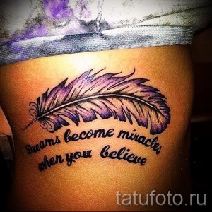 Фото тату пера с надписью "Dreams become miracles when you believe" на бедре. Яркий рисунок с использованием фиолетовых и черных оттенков.