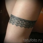 Фото тату: черная татуировка с изображением кружевной подвязки на ноге. Изображение демонстрирует детализированный рисунок татуировки в стиле графика.