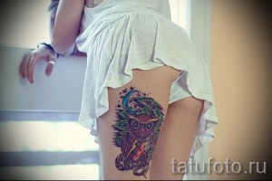 Фото акварельной татуировки совы на бедре. Яркие цвета, размытые контуры и эффект брызг краски создают неповторимый образ.