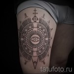 Фото тату на бедре: геометрический узор с изображением глаза в центре. Рисунок татуировки выполнен в черном цвете, с использованием прямых линий и кругов.