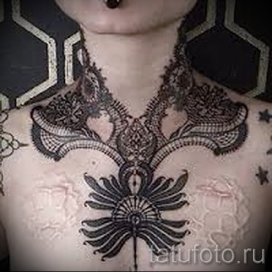 Фото тату: Изящный кружевной узор, покрывающий грудь и плечи. Выполнен в черно-белой графике, создает эффект нежной и воздушной ткани.