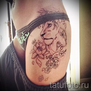 Фото тату на бедре: изображение льва и цветка лотоса в линейном стиле. Эскиз татуировки выполнен тонкими линиями, сочетая дикую природу и духовность.