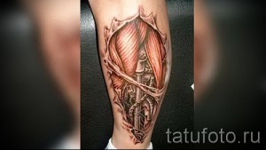 Фото тату: реалистичная биомеханическая татуировка на икре, имитирующая разрыв кожи с видимыми механизмами внутри. Выполнена в черно-серых тонах.
