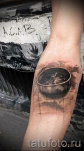 Фото татуировки на руке: небольшой компас, выполненный в черно-серых тонах. Простой и лаконичный дизайн, символизирующий направление.