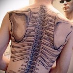 Фото татуировки на спине с изображением человеческого скелета. Детализированный рисунок, выполненный в черно-белых тонах.