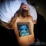 Фото татуировки на лопатке с изображением окна, через которое виден тропический пляж с пальмами и звездным небом. Реалистичный и объемный рисунок.