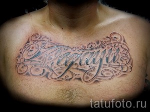 Фотография большой татуировки с именем 'Agatha', выполненной в декоративном стиле с использованием растительных элементов на груди мужчины.