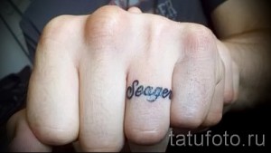 Фото татуировки с именем 'Seager' на костяшке пальца. Черно-серый рисунок татуировки, выполненный простым шрифтом.