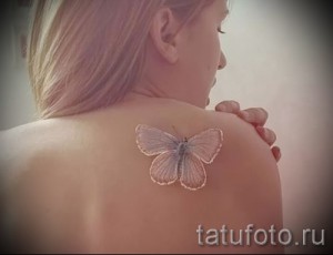 Фото белой татуировки бабочки на женской спине. Деликатный и воздушный рисунок, выполненный в технике white tattoo.
