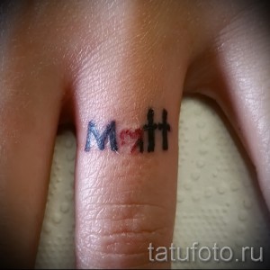 Фотография небольшой татуировки с именем 'Matt', выполненной в черно-красной гамме на пальце руки. Идеально для любителей минимализма.