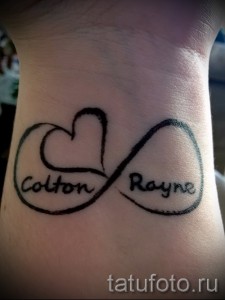 Фото татуировки с именами 'Colton' и 'Rayne', заключенными в символ бесконечности на запястье. Черно-серый рисунок татуировки, выполненный в минималистичном стиле.