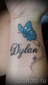 Фото татуировки с именем 'Dylan' и изображением голубой бабочки на запястье. Цветной рисунок татуировки, выполненный в реалистичном стиле.