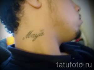 Фотография небольшой татуировки с именем 'Maya', выполненной простым шрифтом на шее.