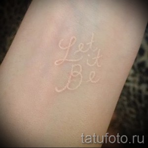 Фото тату надписи 'Let it Be', выполненной белыми чернилами на запястье, в минималистичном и изящном стиле.