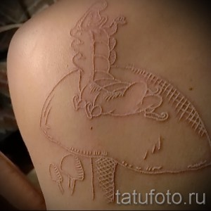 Фото тату белого дракона на лопатке, выполненного в технике white ink, с детальной проработкой крыльев и чешуи.