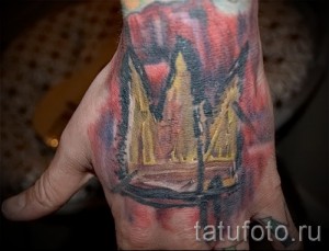 Фото татуировки на руке с изображением короны, охваченной пламенем, выполненной в ярких и насыщенных цветах.