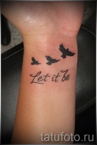 Фото татуировки на запястье с изображением трех летящих птиц и надписи 'Let it be', выполненной в черном цвете.