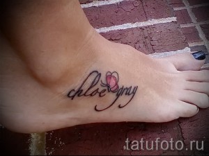 Фото тату надписи 'Chloe Gray' и маленького сердечка на стопе девушки. Татуировка выполнена в черных чернилах, с изящным шрифтом.