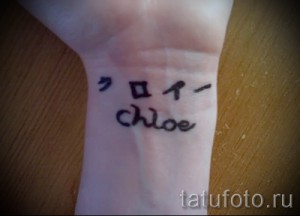 Фото тату с надписью 'Chloe' и иероглифами на запястье. Небольшой рисунок татуировки, выполненный черными чернилами.