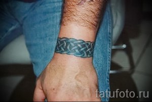 Фото татуировки на запястье: кельтский узор в виде узла, выполненный в темно-зеленых тонах.