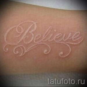 Фото белой татуировки с надписью 'Believe' выполненной красивым шрифтом. Деликатный и вдохновляющий рисунок.