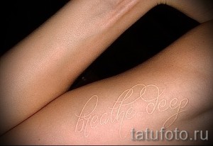 Фотография белой татуировки с надписью 'breathe deep' на коже, выполненной тонкой линией. Изящный минимализм для ценителей.