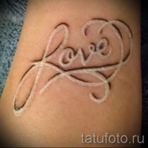 Фото белой татуировки на руке с надписью 'Love' и декоративными завитушками. White ink, романтичный стиль, женственная идея для тату.