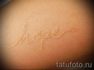 Фото белой татуировки на спине с надписью 'hope'. Минималистичный дизайн, white ink, вдохновляющий рисунок, женственная татуировка.