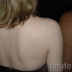 Белая татуировка - стрекоза на лопатке
