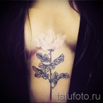 Белая татуировка - цветок между грудей у девушки