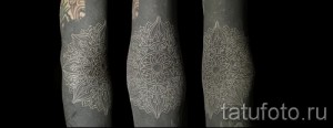 Фотография белой татуировки в виде мандалы на руке. Сложный и красивый узор.