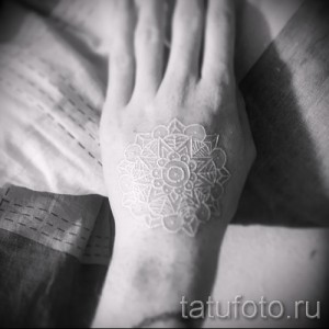 Фото тату: сложная белая татуировка в виде мандалы, расположенная на тыльной стороне руки, выполненная в технике white ink.