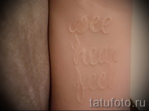 Фото тату: минималистичная белая татуировка с надписью 'See Hear Feel' на руке, выполненная в технике white ink.