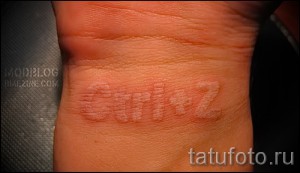 Фото тату: минималистичная белая татуировка с надписью 'Girl+2' на запястье, выполненная в технике white ink.