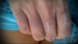 Фото белой татуировки: надпись 'LOVE', выполненная на пальцах в технике white ink, создающая нежный и романтичный образ.