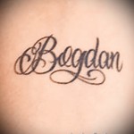 Фото тату с именем 'Bogdan', выполненное в черном цвете в каллиграфическом стиле. Изящные завитки и плавные линии придают татуировке элегантность.