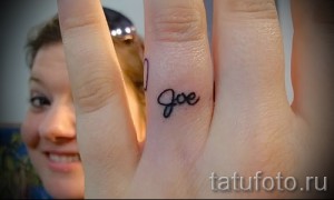 Фото татуировки на пальце: надпись 'Joe' выполненная тонким черным контуром. Простой и элегантный дизайн.