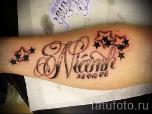 Фото татуировки с именем 'Niamh', датой '11.06.88' и черными звездами, выполненной на предплечье в красно-черной гамме.