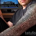 Фото тату, имитирующее змеиную кожу, покрывающую руку. Детализированный и реалистичный рисунок с текстурой чешуи.