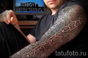 Фото тату, имитирующее змеиную кожу, покрывающую руку. Детализированный и реалистичный рисунок с текстурой чешуи.