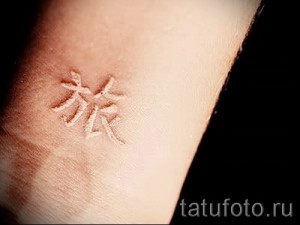 Фото белой татуировки иероглифов на запястье. Небольшой рисунок с восточными символами. Эскиз тату с культурным значением.