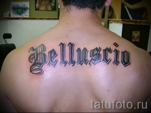 Фото тату с именем 'Belluscio' на спине мужчины, выполненное черными чернилами в классическом стиле.