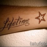 Фото тату с надписью 'Lifetime' и звездой на руке. Красный шрифт и контур звезды. Простой и символичный дизайн.