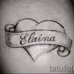 Фото тату сердца с именем «Elaina» на руке. Черно-белая татуировка выполнена в минималистичном стиле с тонкими линиями.