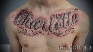 Фото тату надписи 'Charlotte' на груди мужчины, выполненной в стиле леттеринг с декоративными элементами и эффектом объема.
